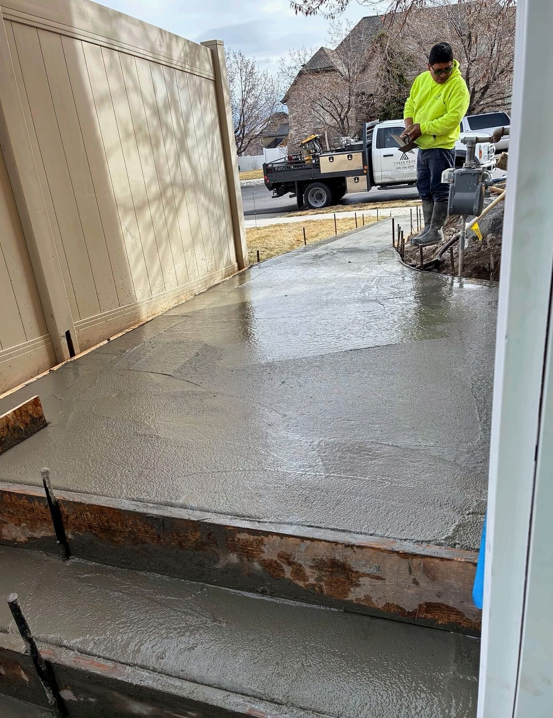 Crew member finishing a new concrete walkway and entry steps